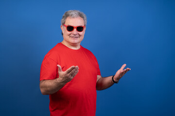 Naklejka premium A man in a red shirt is wearing sunglasses and pointing to the sky