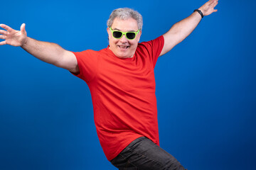 Naklejka premium A man in a red shirt and green sunglasses is smiling and posing for a picture