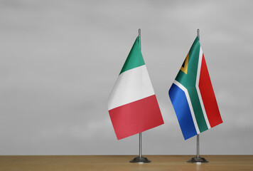 Table flags of Italy and South Africa on grey blurred background