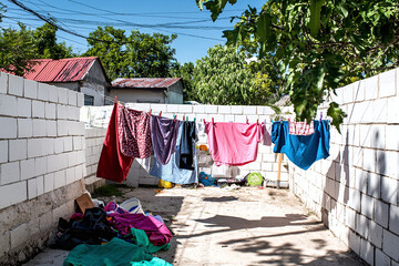 a quaint backyard with freshly washed clothes drying in the sun, framed by rough-hewn white ceramic block walls