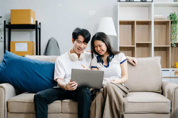 Smiling couple enjoying casual moments on the couch with a laptop, showcasing teamwork, laughter, and a relaxed