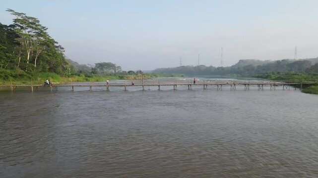 Aerial footage shows a wooden bridge spanning the Progo River, passable by motorbikes. As a link between the villages of Bantul and Kulonprogo.