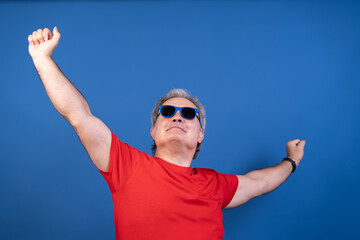 Naklejka premium A man in a red shirt is wearing sunglasses and is raising his arms in the air