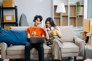 Smiling couple enjoying casual moments on the couch with a laptop, showcasing teamwork, laughter, and a relaxed