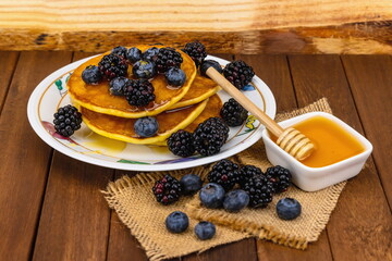 Pancake con ciotola di miele , more e mirtilli