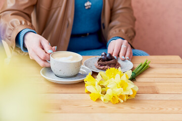 Petite dessert - stylish coffee break with vibrant yellow flowers daffodils