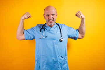 A bald doctor flexes his biceps showing strength.