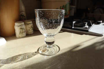 The sunny kitchen still-life of a crystal wine glass with clear bubbles in the glass.