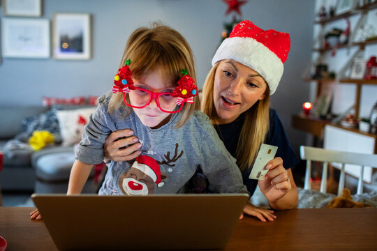 Mom and kid doing Christmas online shopping with laptop and credit card