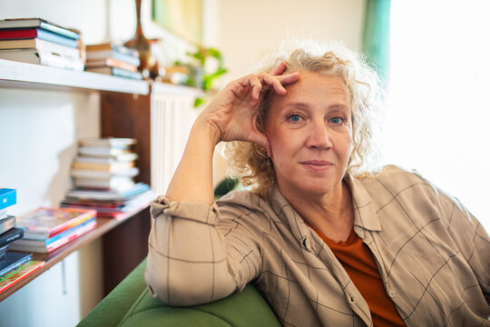 Portrait of a confident middle aged woman sitting on couch looking directly at camera