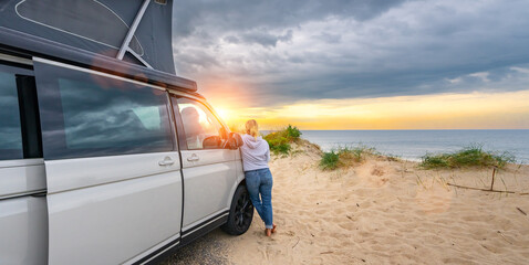 Young traveller woman with her Transporter Camping Van bus at the California Ocean in the coastal...