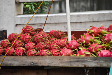 Vibrant ripe dragon fruit piled together on a cart for sale in a flea market