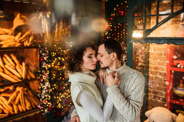 Fototapeta premium couple in love hugging on a background of lights and a Christmas tree