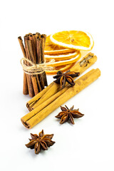 Cut orange and different spices  on white background. Traditional festive winter beverage.Cinnamon, dried orange, anise and cloves