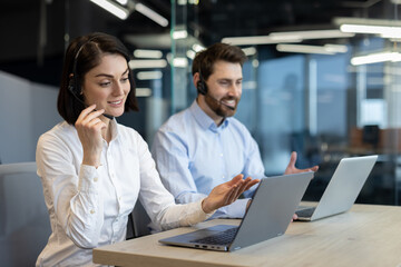 Naklejka premium Office professionals engaged in virtual meeting, wearing headsets, using laptops. Worker collaboration and communication concepts displayed through technology in professional workspace