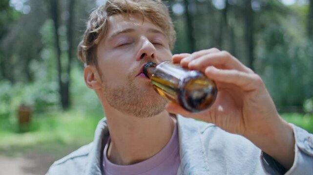Man drinking beer picnic in sunlit forest closeup. Portrait relaxed guy relaxing