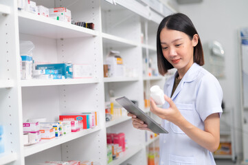 Asian professional female pharmacist using tablet to check drug list Pharmacist checking stock in pharmacy for health medicine in technology pharmacy looking at camera smiling