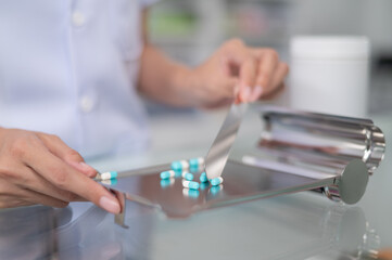 Asian professional female pharmacist standing with arms crossed looking at camera charming smile pointing hand to pill bottle health care products in pharmacies Close-up and wide-angle shots