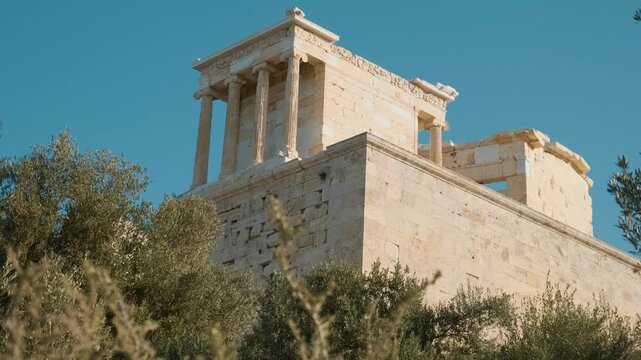 Temple of Athena Nike on the hill in Acropolis against blue sky, Athens, Greece. Fully Ionic temple on the Acropolis. Ancient greek architecture. Popular travel and touristic landmark