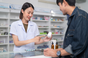 Fototapeta premium Asian professional female pharmacist using a digital tablet computer to dispense prescription medication to male customers. The doctor advises and explains to the client about the medication.