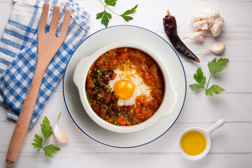 Spanish tapa of baked egg with chorizo ​​and tomato. Top view table with  decorations.