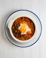 Spanish tapa of baked egg with chorizo ​​and tomato. Top view table with  decorations.
