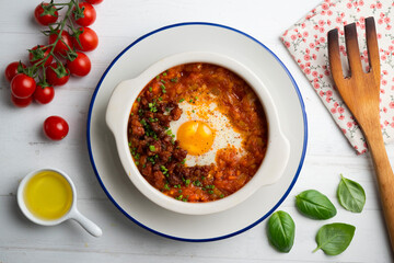 Spanish tapa of baked egg with chorizo ​​and tomato. Top view table with  decorations.