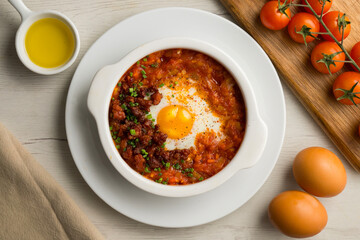 Spanish tapa of baked egg with chorizo ​​and tomato. Top view table with  decorations.
