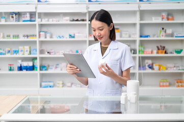 Asian professional female pharmacist using tablet to check drug list Pharmacist checking stock in pharmacy for health medicine in technology pharmacy looking at camera smiling