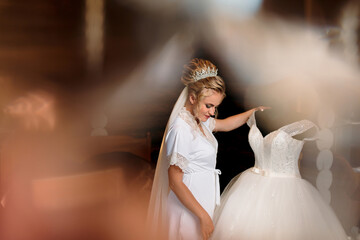 Fototapeta premium A bride is looking at a wedding dress hanging on a rack