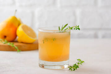 Pear drink cocktail with lemon, rosemary, thyme and ice in a glass on a white table. Healthy drink,...
