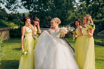 A bride and her bridesmaids are walking down a path in a garden