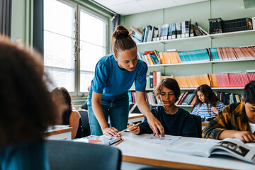 Female teacher helping boy with creativity in drawing class at elementary school