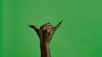 Creepy halloween devil monster hand in black paint with nails shows call me a gesture, isolated on...