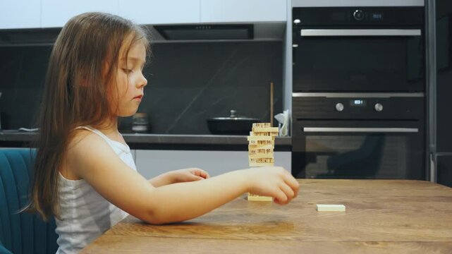 Wooden block tower game, child girl joyfully plays with colorful wooden blocks, enhancing creativity and coordination through this activity that promotes imagination, independence, playful learning