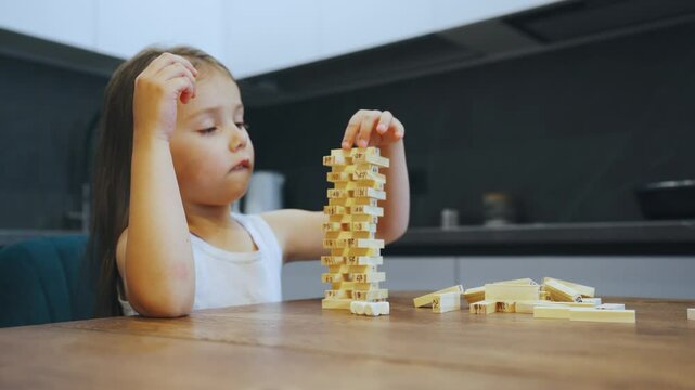 Wooden block tower game. A young child is happily engaged in playing with a wooden block tower game, surrounded by the warmth and comfort of a cozy kitchen environment filled with love and creativity