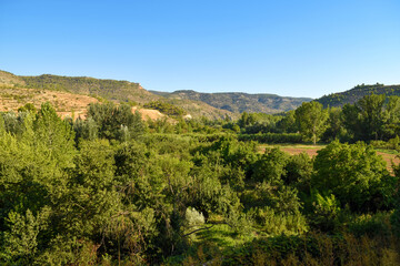 Nature background of mountains, groves, and orchards along the Turia River valley as it passes through the Rincón de Ademuz near Casas Altas on the Iberian Peninsula