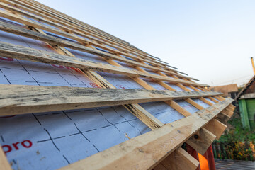  lose-up of a wooden roof frame during construction. The wooden planks are arranged in a grid pattern and supported by beams, creating a sturdy foundation for the roof.