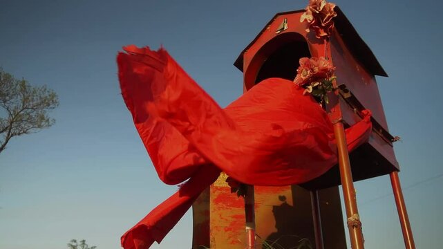 Slow-motion, low angle view of a roadside shrine honoring popular saint Gauchito Gil