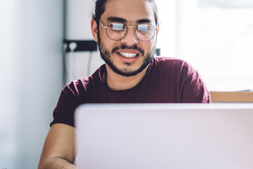 Smiling casual student using laptop