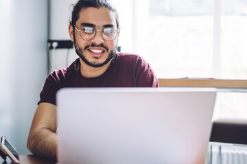 Smiling casual student using laptop