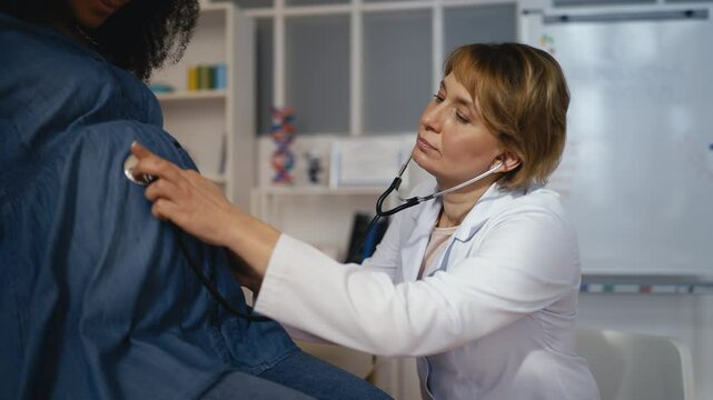 Woman gynecologist monitoring fetal heart rate with stethoscope, check-up