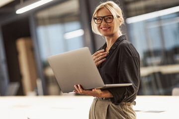 A Professional Woman Working on a Laptop in a Contemporary and Modern Office Environment