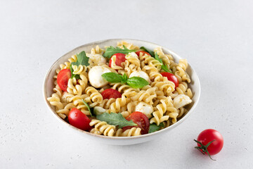 Italian cold salad with fusilli pasta, cherry tomatoes, mozzarella, arugula.