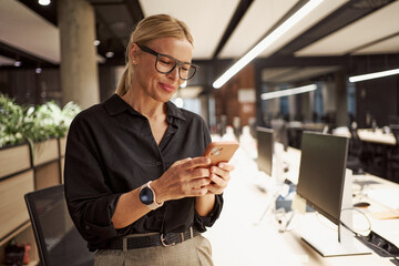 A professional woman is skillfully using her smartphone in a vibrant modern office setting
