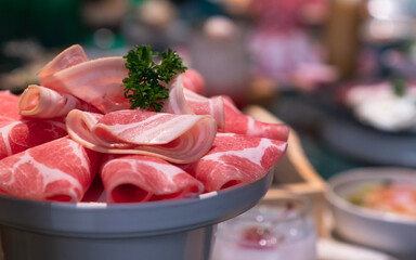 Sliced belly pork for shabu, sukiyaki, or Japanese hot pot with restaurant background.