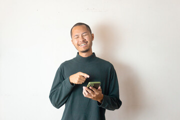 Young asian men wearing winter clothes or sweater is laughing while holding smartphone on isolated white