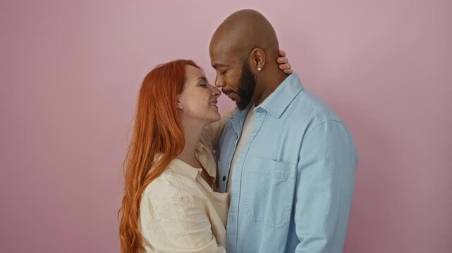 Couple embracing with love over pink background, depicting an interracial relationship between a man and a woman, showing genuine affection and togetherness