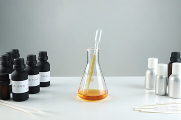 chemical beaker , flask is on white table with blotting paper , fragrance bottle and essential oil...