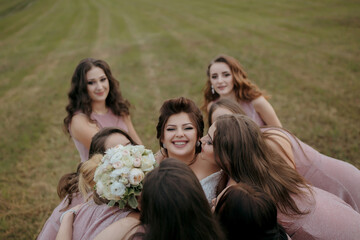 A group of women are hugging and kissing each other, with one woman holding a bouquet of flowers. Scene is joyful and celebratory